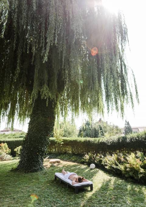 Blick auf einen idyllischen Garten mit Weidenbaum im Antoniushof