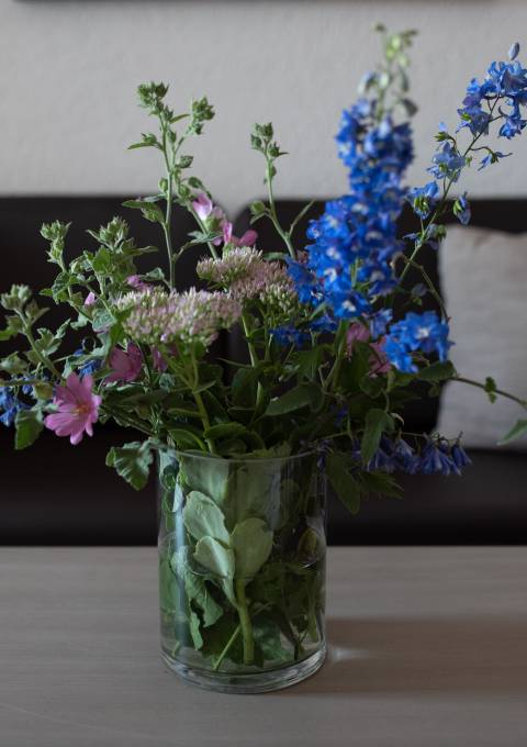 Frischer bunter Blumenstrauß in Glasvase auf Holztisch im Antoniushof Hotelzimmer