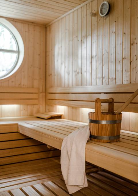 Holz-Saunaraum mit einem Aufgusskübel und stilvoller Einrichtung