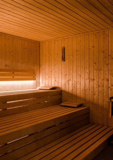 Innenansicht der Finnischen Sauna mit warmem Licht und Holzbänken im Antoniushof Wellnesshotel in Ruhstorf an der Rott