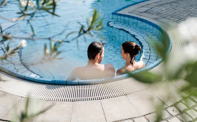 Paar entspannt sich im Außenpool des Antoniushofs, umgeben von Natur und ruhiger Atmosphäre.