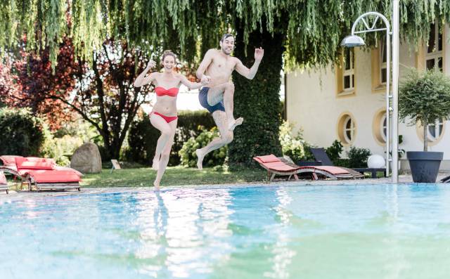 Ein Paar springt voller Freude in den Pool des Antoniushofs.