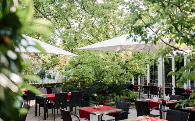 Gartenterrasse mit gedeckten Tischen unter Sonnenschirmen