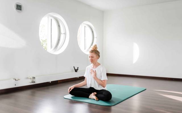 Frau bei Yoga-Übung in einem ruhigen, lichtdurchfluteten Raum