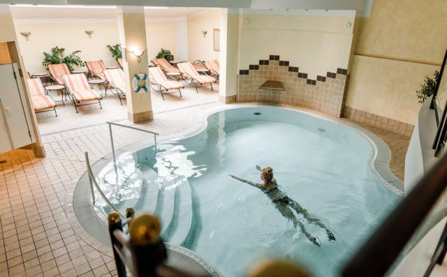 Schwimmende Person im Indoor-Pool des Wellnessbereichs