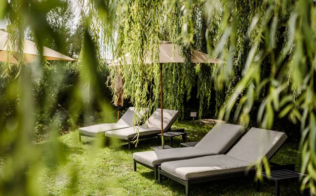 Sonnenliegen im Grünen, umgeben von üppiger Natur im Garten des Antoniushofs