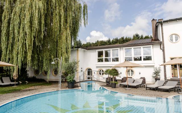 Blick auf den Pool und die Hotelanlage des Antoniushofs im Sonnenschein