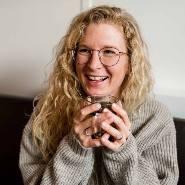 Frau lächelt und hält eine Teetasse in der Hand