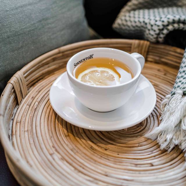 Tasse Kräutertee mit Zitronenscheibe auf Tablett