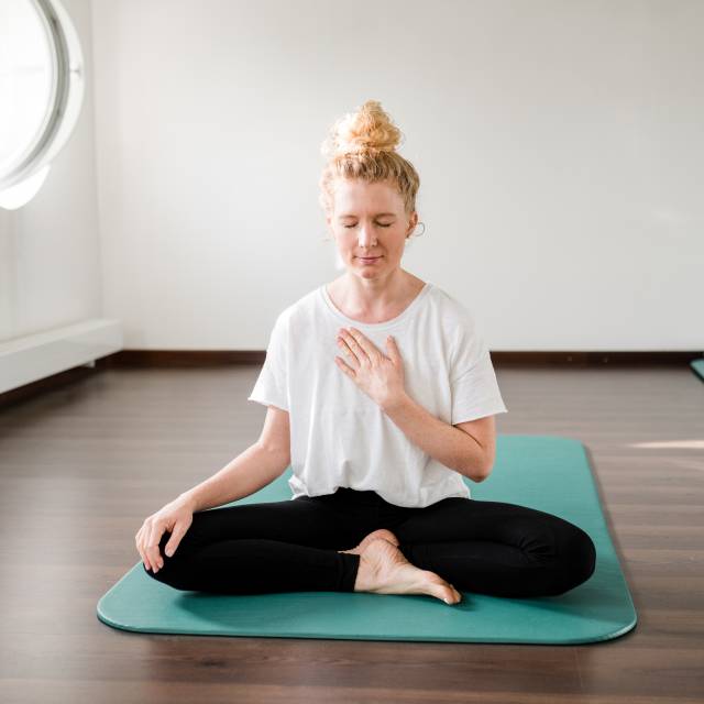 Frau beim Yoga auf einer Matte in einem Fasten- und Wellnesskurs