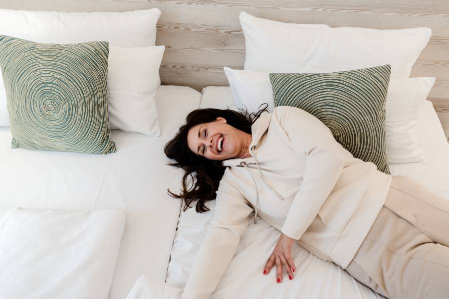 Entspannte Frau genießt Wellnesswochenende im Hotelbett – Ruhe und Erholung im 4-Sterne-Hotel